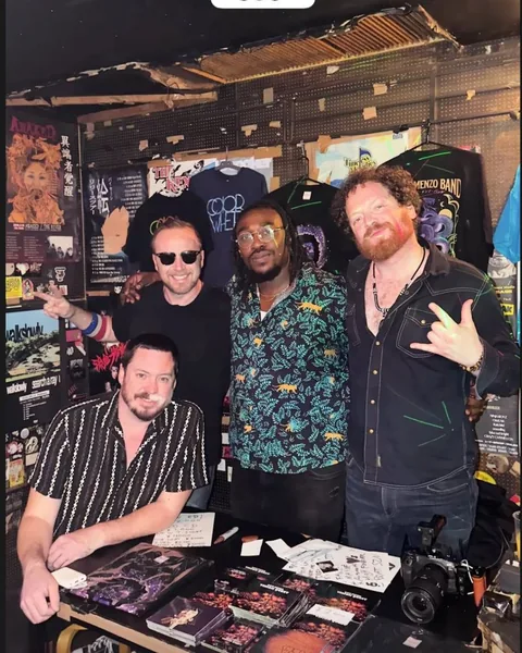 The band at the merch table at Livehouse WALL, Hatsudai, with Vision Quest CDs and tour shirts